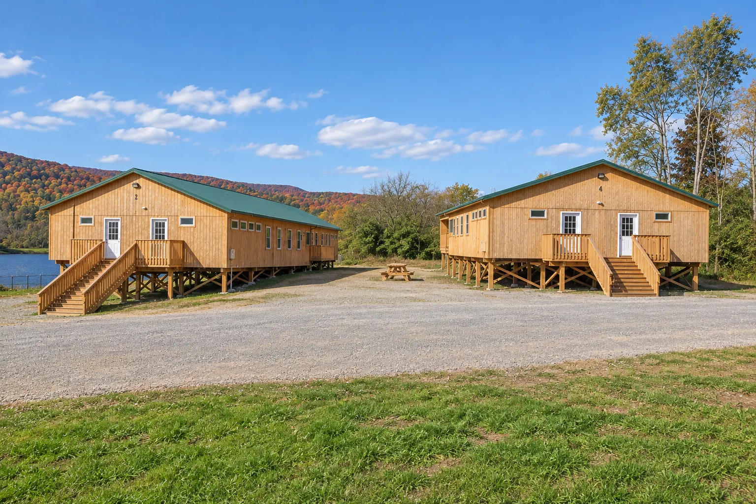 Two new camp bunkhouses on raised foundations beside a lake in Sullivan County