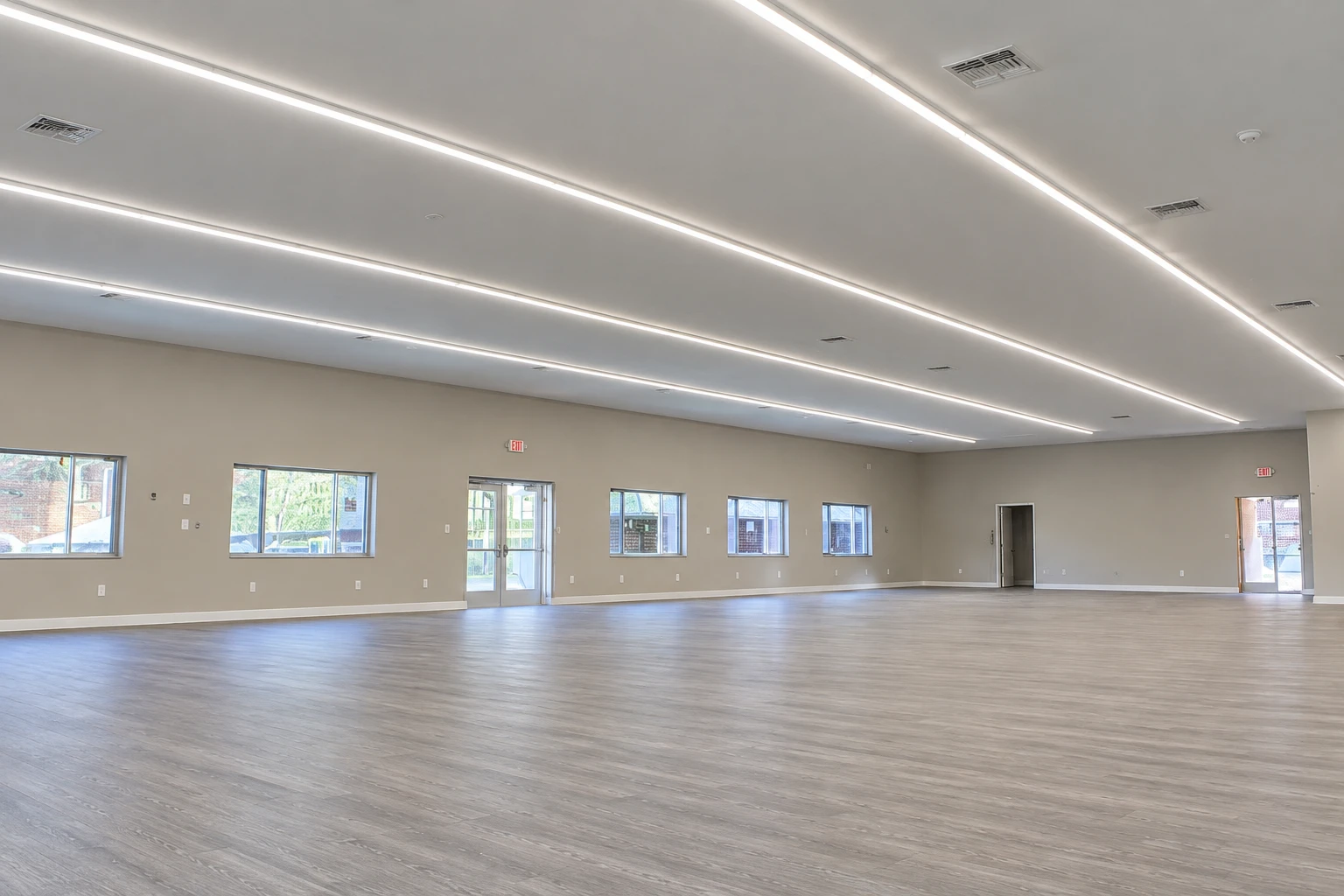 Large finished beis medrash with linear ceiling lights and wood-look flooring